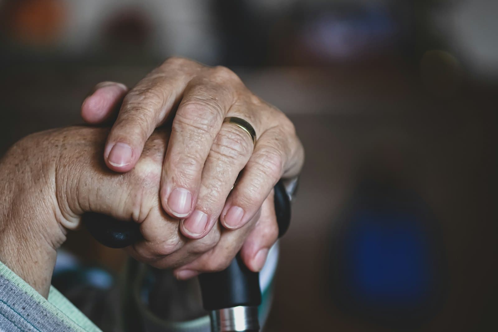 An older person's hands resting on a cane