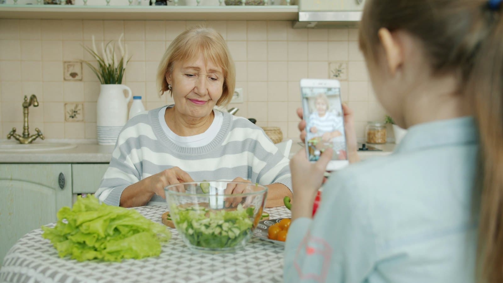 A grandmother and granddaughter making a salad in the kitchen