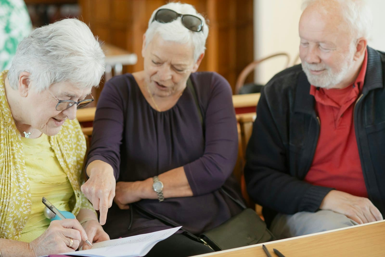 Three older adults reading over a document together
