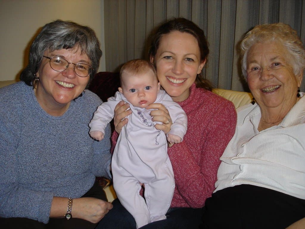 Four generations of women on a sofa: a great-grandmother, grandmother, mother and baby