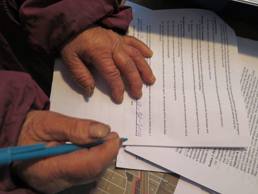 An older person's hands signing a printed document with a pen